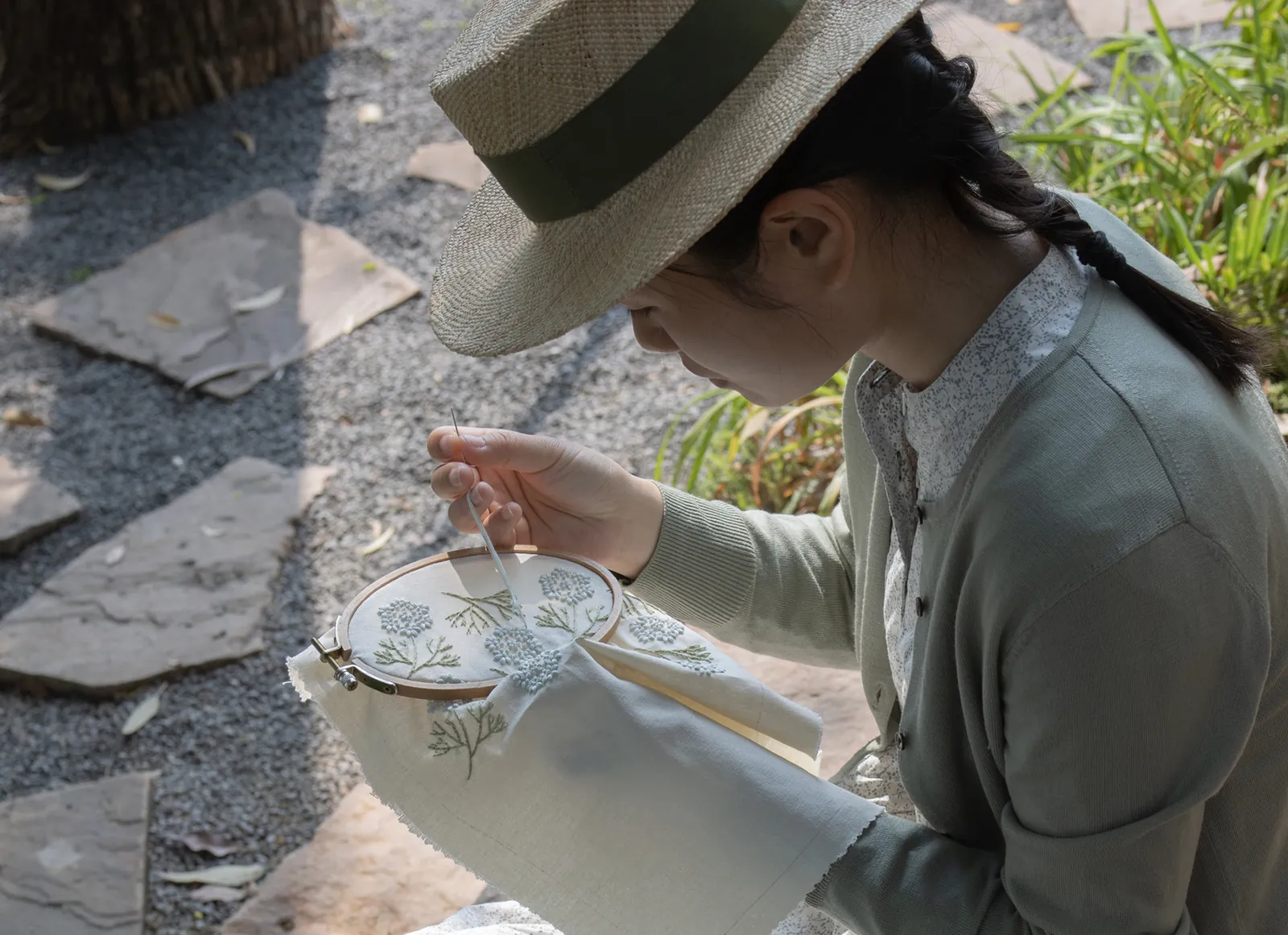 Lissy Luo hand-stitching a delicate floral embroidery outdoors