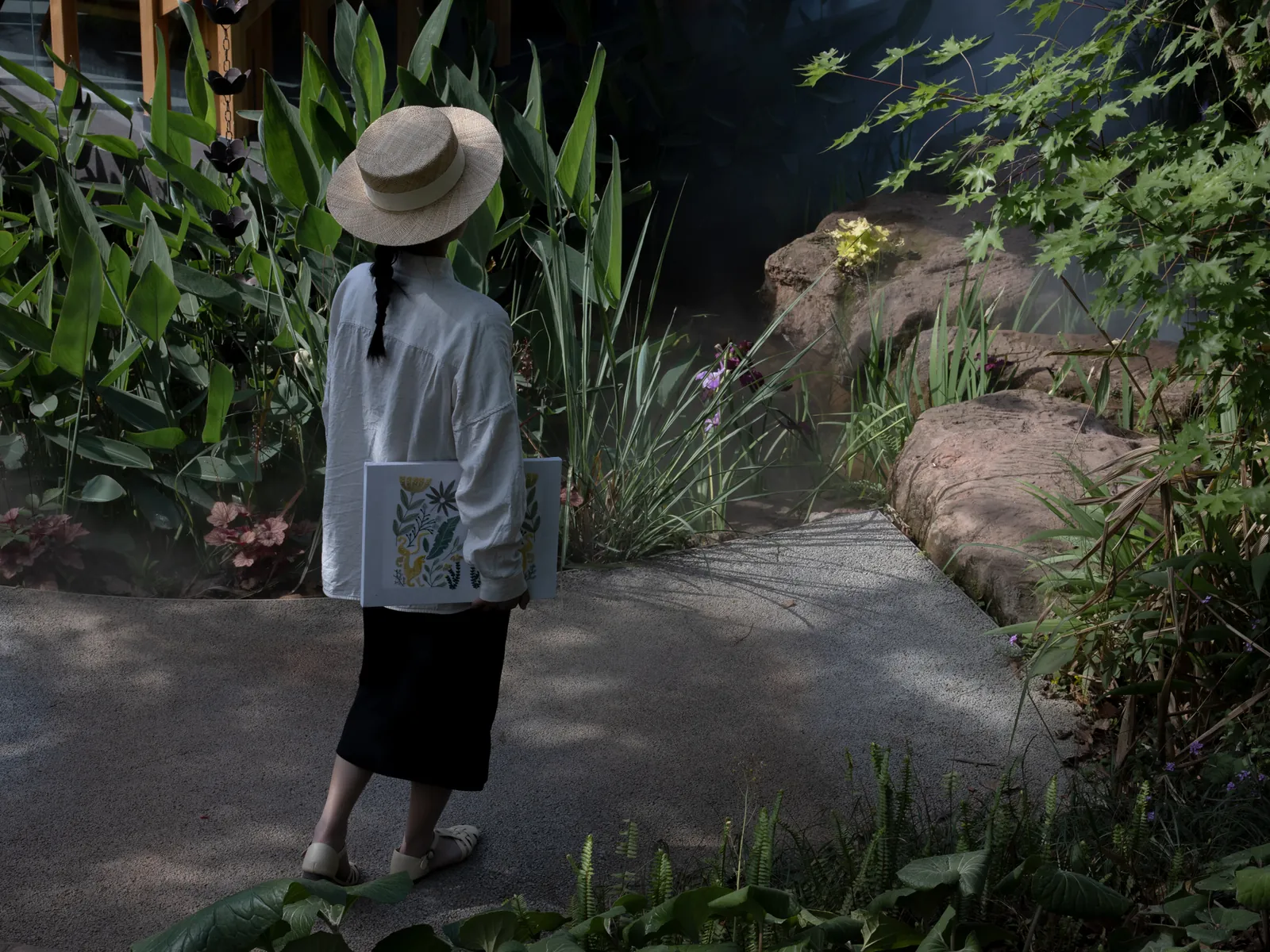 A hand-embroidered artwork carried through a lush garden